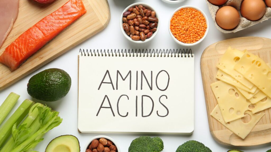 Cuaderno con la palabra 'AMINO ACIDS' junto a alimentos saludables, destacando la importancia de los 10 aminoácidos no esenciales en la alimentación diaria.