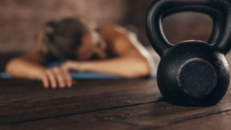 Atleta descansando después de una sesión de entrenamiento para aumentar la masa muscular con una pesa rusa en primer plano.