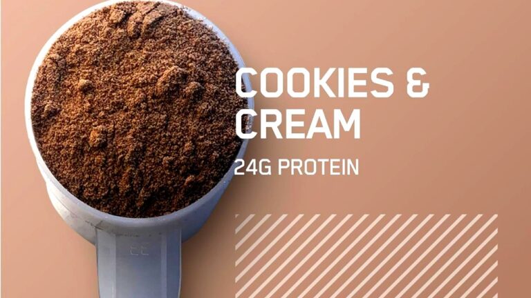 Primer plano de una cucharada de Optimum Nutrition Gold Standard Whey sabor Cookies & Cream sobre un fondo con textura, resaltando los 24 gramos de proteína por porción