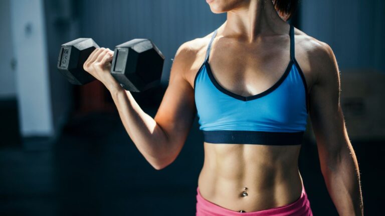 Levantadora de pesas enfocada demostrando fuerza, ilustrando la potencia obtenida de componentes de suplementación deportiva.