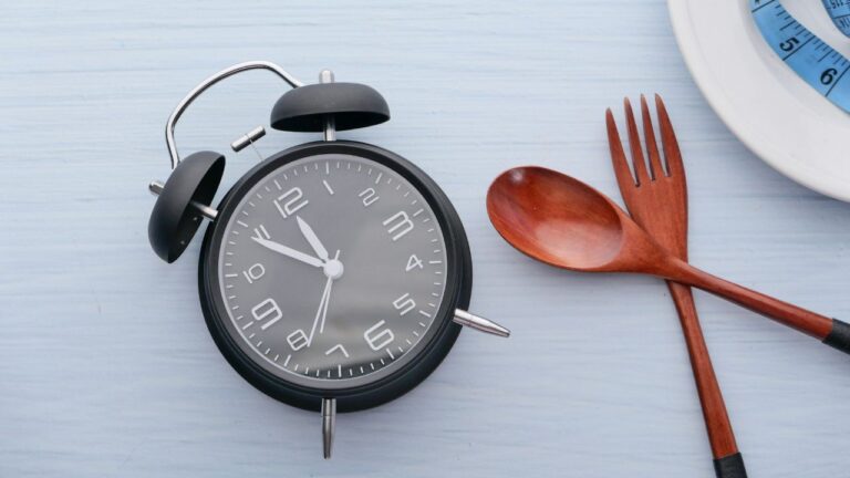 Reloj y utensilios simbolizando el momento óptimo para la ingesta de suplementos pre entreno.