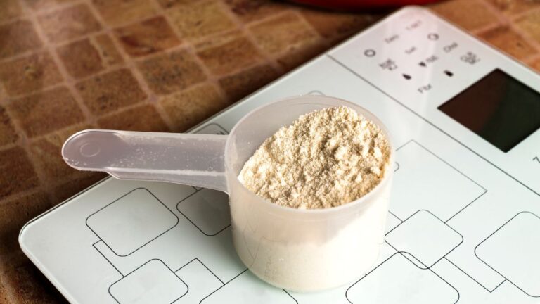 Suplemento de pre entreno en polvo sobre una báscula de cocina, enfatizando la precisión en la dosificación para el ejercicio.