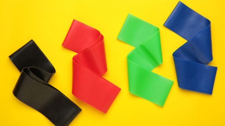 Colección colorida de bandas elásticas sobre fondo amarillo para entrenamiento en casa