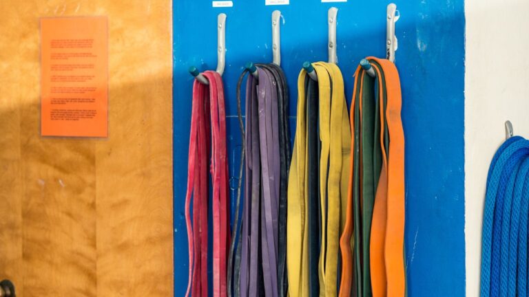 Bandas elásticas de distintas resistencias colgadas en una pared azul, listas para el uso