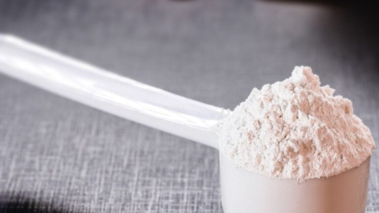 Cuchara medidora con polvo de creatina monohidrato, suplemento para el pre-entrenamiento.