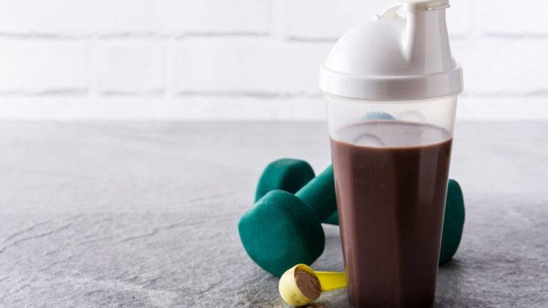 Shake de proteína listo para consumir al terminar la sesión de ejercicios, con mancuernas al lado.