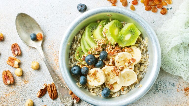 Bowl nutritivo de quinoa y avena con rodajas de kiwi y plátano, acompañado de arándanos, ideal para un desayuno energético.