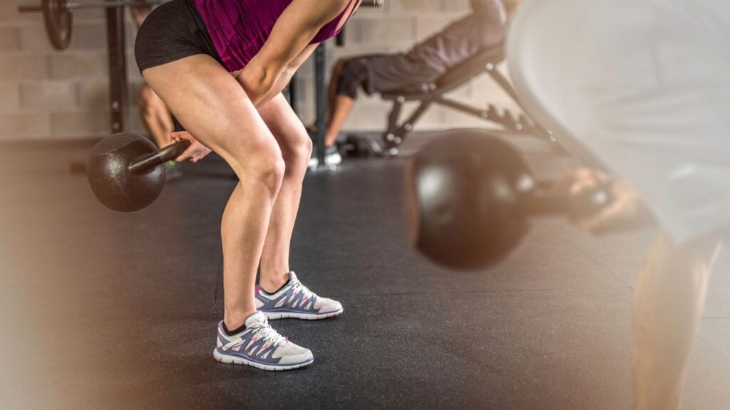 Realización de ejercicios con kettlebell para fortalecimiento de glúteos por parte de una atleta en el gimnasio