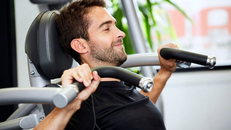 Ejercicio de press militar en máquina de gimnasio para fortalecer los deltoides.