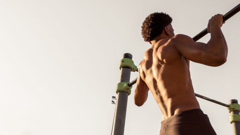 Atleta masculino al aire libre preparándose para hacer ejercicio en una barra de dominadas portátil.