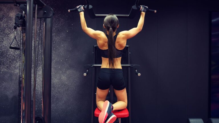 Rutina de entrenamiento en progreso con un hombre completando una serie de dominadas en un gimnasio moderno.