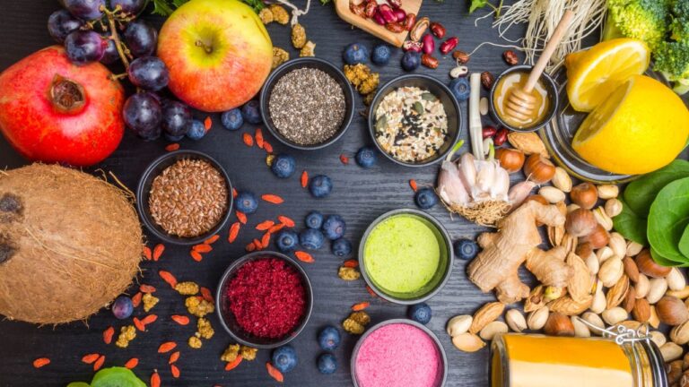 Alimentos con alto contenido de compuestos antioxidantes, incluyendo frutas, frutos secos y especias, sobre fondo oscuro.