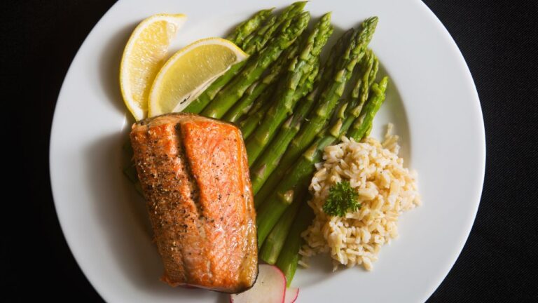Filete de salmón a la plancha con un lado de espárragos verdes y una porción de arroz integral, una comida equilibrada para deportistas