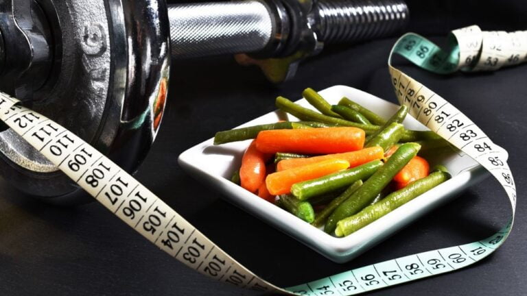 cinta de medir, un plato saludable y unas mancuernas que simbolizan una imagen de como perder peso rápido