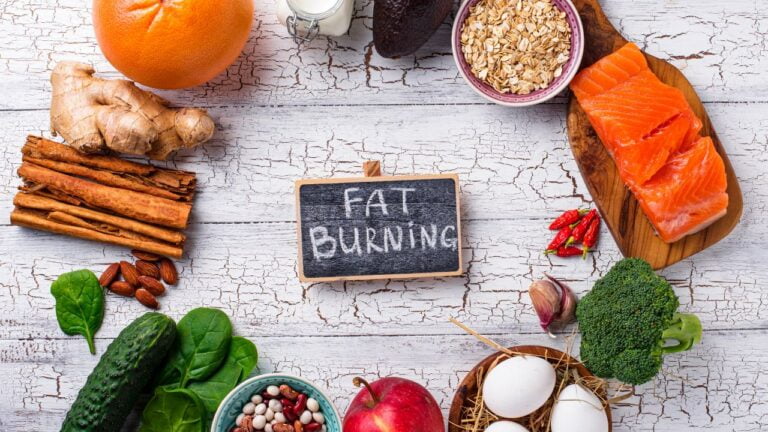 un conjunto de frutas rodeando una pizarra con la palabra 'fat burning' refiriéndose a una dieta sobre como perder peso