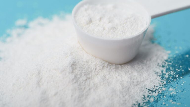 Creatina monohidrato en cuchara verde, destacando la suplementación para el aumento de rendimiento muscular.