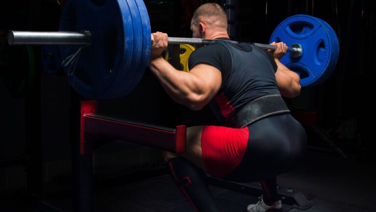 Realización de sentadillas con barra en el gimnasio para trabajar la musculatura inferior.