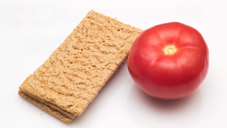 Pan wasa junto a un tomate maduro, combinación ideal para un snack ligero y saludable.