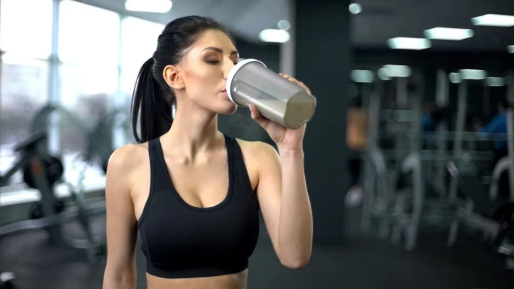 Una atleta bebiendo un batido de proteína posentrenamiento, una elección popular para la recuperación muscular.