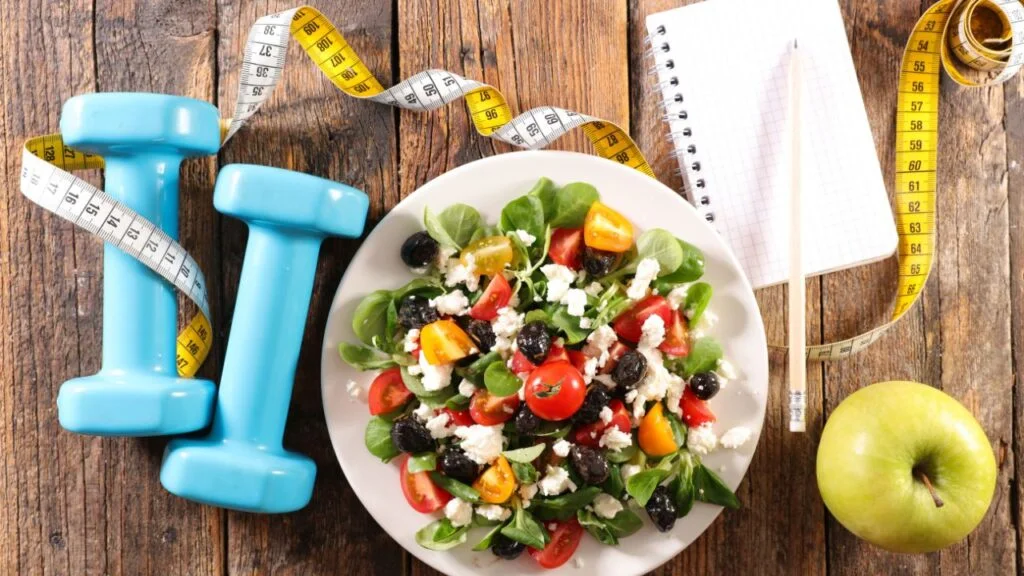 Ensalada fresca con espinacas y pesas azules, mostrando la combinación de ejercicio y alimentación saludable para una vida activa.