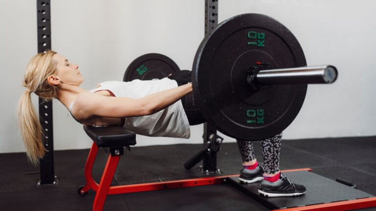 Mujer realizando ejercicio de empuje de caderas con barra para potenciar la fuerza glútea.