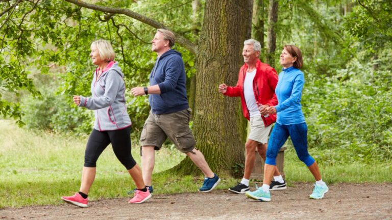 Un grupo de adultos activos disfrutando de un paseo energético en un bosque, una actividad perfecta para un estilo de vida saludable y activo.