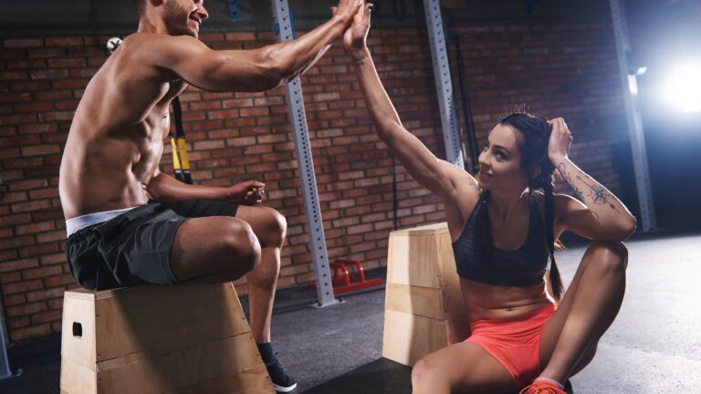 Dos atletas se dan la mano en un gesto de apoyo mutuo tras completar un circuito de ejercicios funcionales, reflejando el espíritu de comunidad en las rutinas de CrossFit caseras.